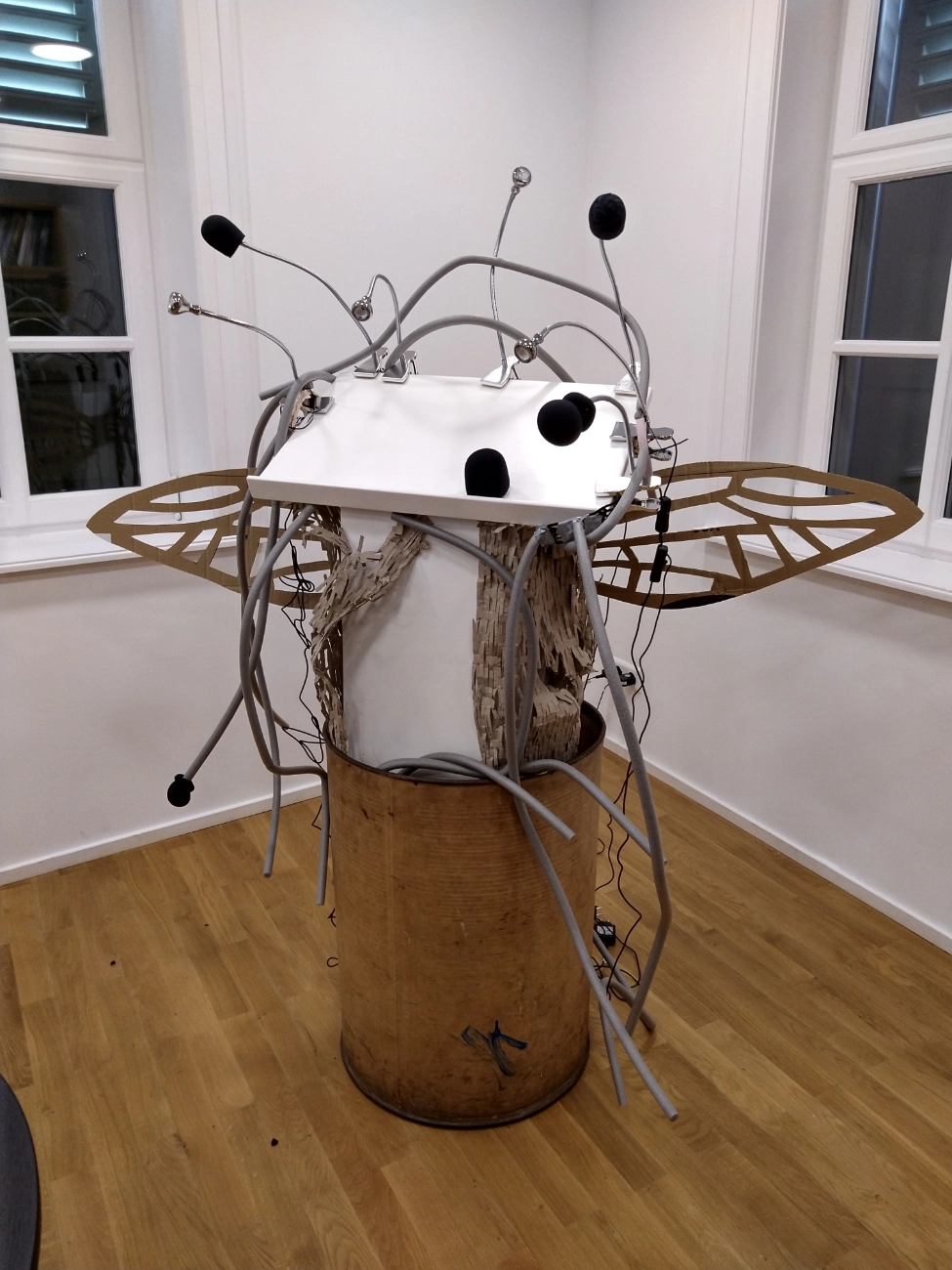 Ein Stehpult mit Insektenfl&uuml;geln und mehreren Mikrofonarmen, als w&auml;ren es F&uuml;hler.