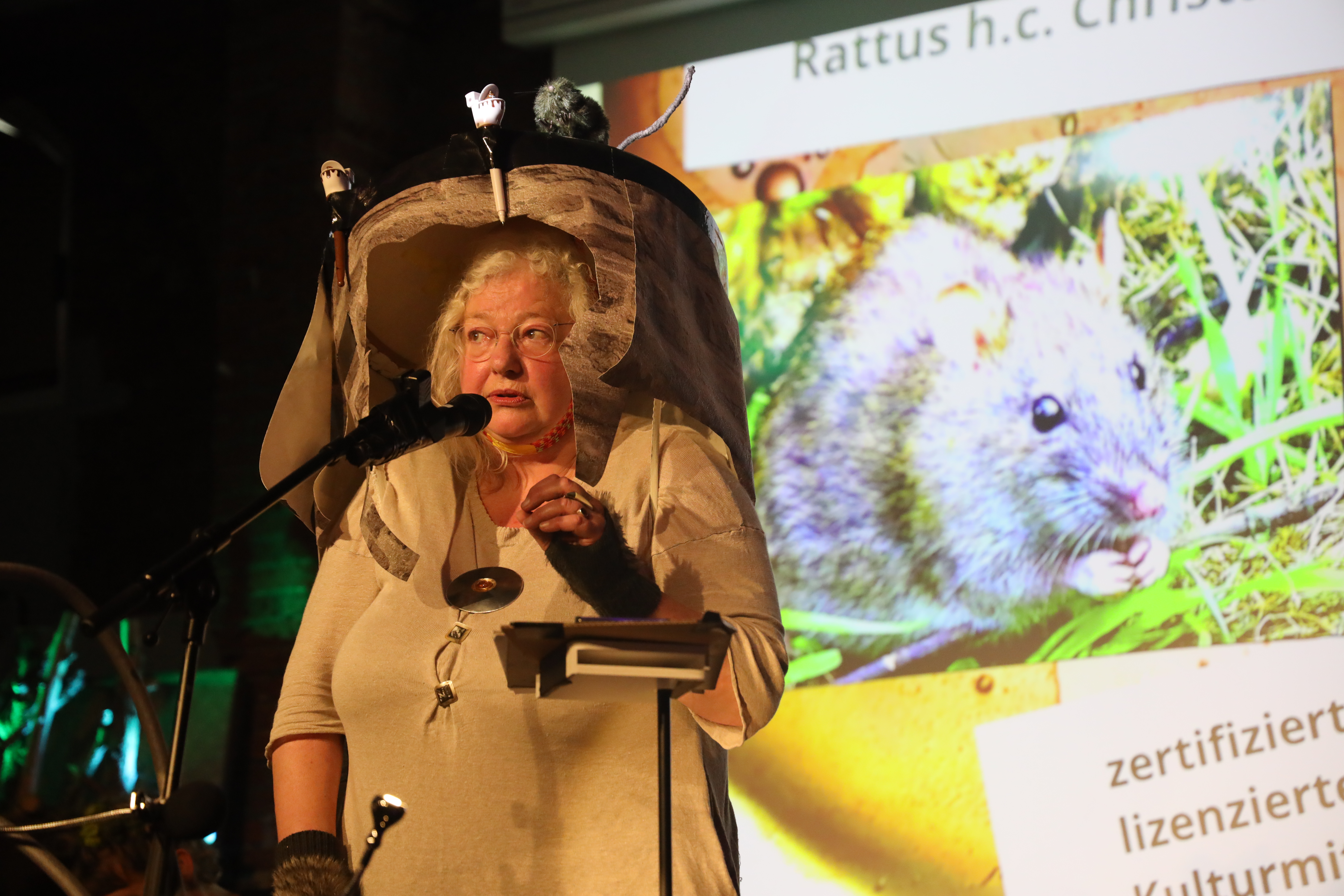 Frau mit Kostüm einer Kanalratte steht auf als Botschafterin dieser Wesen auf einer Bühne.
